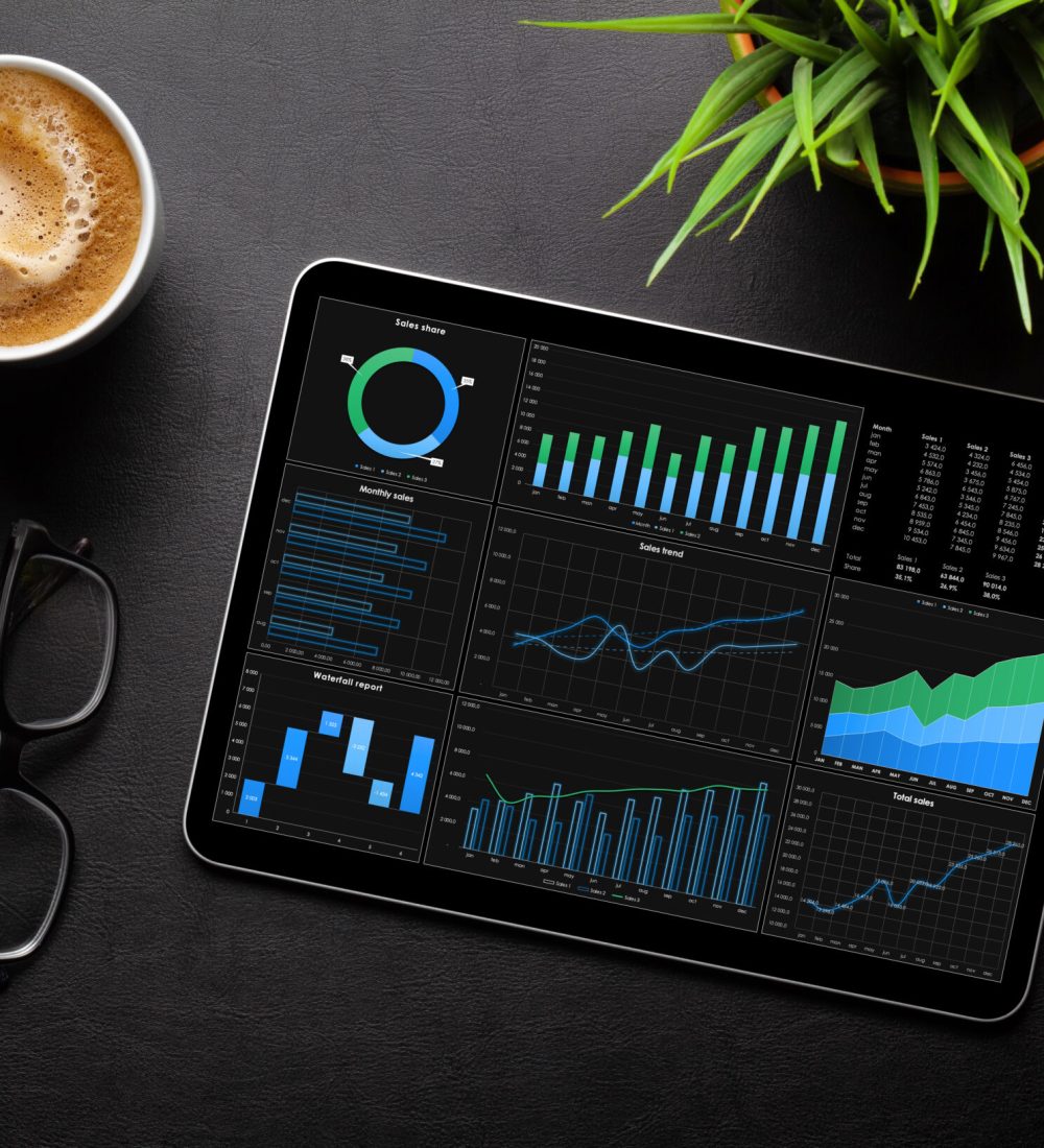 Tablet with business reports and charts, coffee cup and office supplies on desk. Top view flat lay