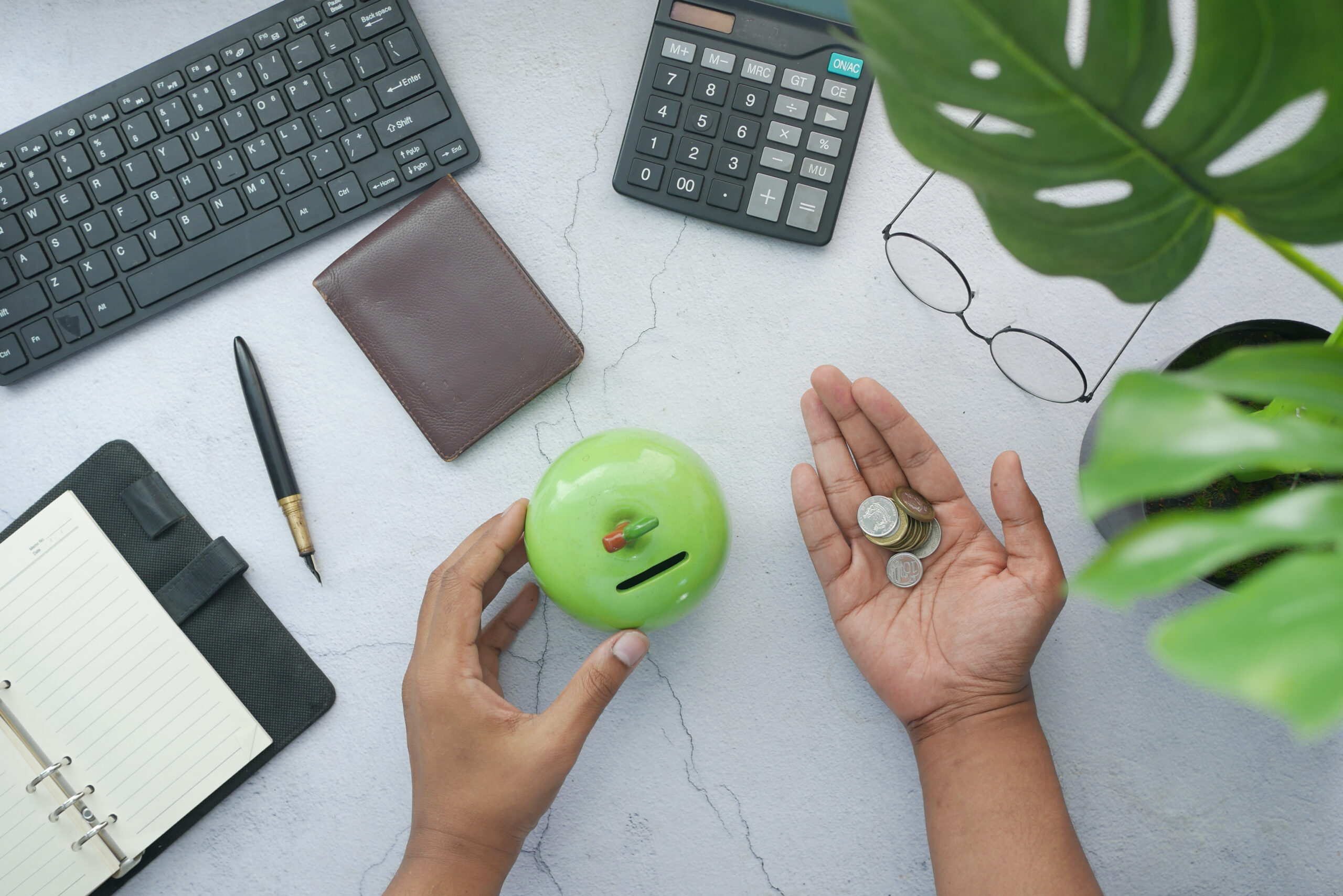 young man saving coins in a jar and writing on notepad .