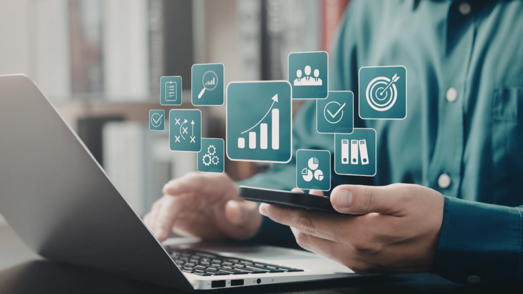 Hands holding a smartphone with floating analytics icons (charts, checkmarks, gears) over a laptop screen beside it, illustrating data analytics.